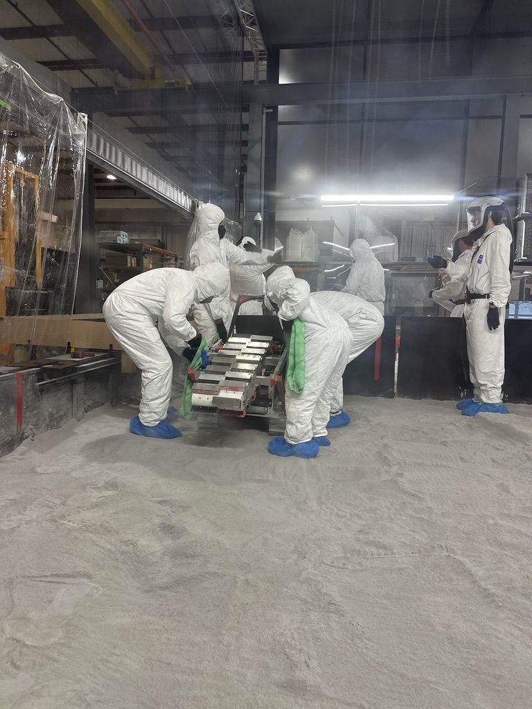 Team members carrying the rover across the arena regolith